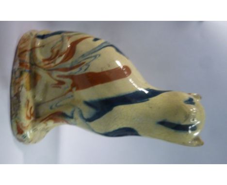 An early 19thC Delftware model novelty seated cat money bank, decorated in streaky iron red and blue, on a honey coloured gro