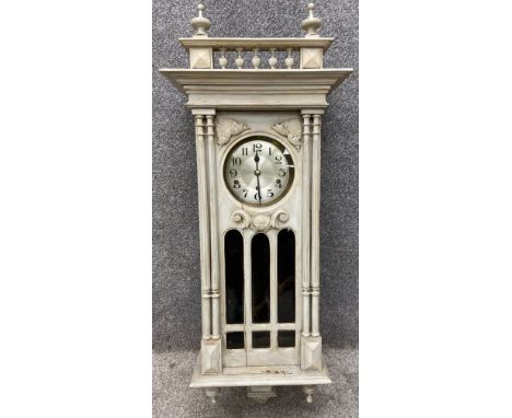 A late 19th/early 20th century carved and painted neoclassical style wall clock with two ball and spire finials on a balustra
