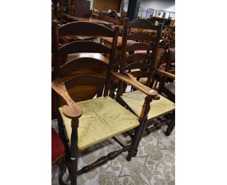 Two period oak ladder back carver chairs having later rush seats