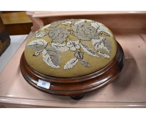 An early Victorian footstool in button design with mahogany frame on turned feet with bead work top