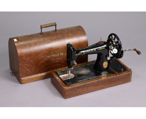 A vintage Singer hand sewing machine, in an oak carrying case.