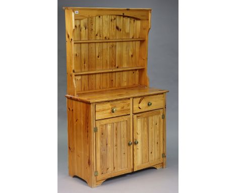 A pine kitchen dresser, the upper part fitted two open shelves and panelled back, the base fitted two frieze drawers above cu