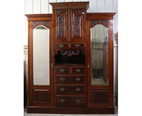 A late 19th/early 20th century carved walnut wardrobe enclosed by a pair of panel doors to centre above an arrangement of fou