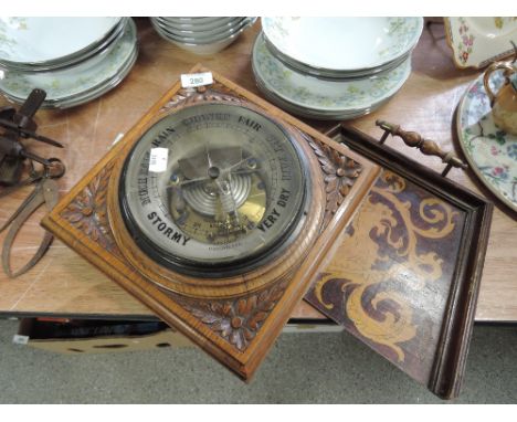 A wall mounted barometer with carved oak frame AF and crumb pan with mythical decoration