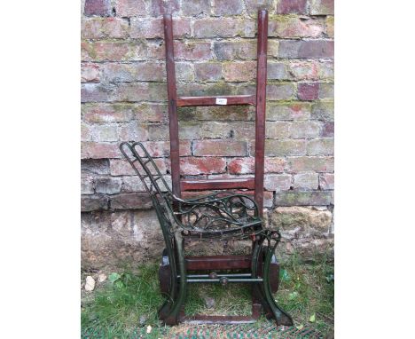 A pair of iron bench ends with scrolled detail and a small primitive sack truck 