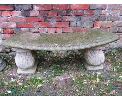 A reclaimed crescent shaped garden bench raised on scrolled supports, 120 cm wide 