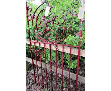 A wrought iron pedestrian or side gate in red painted finish, 88cm wide x 170cm high approx, with scrolling detail and centra