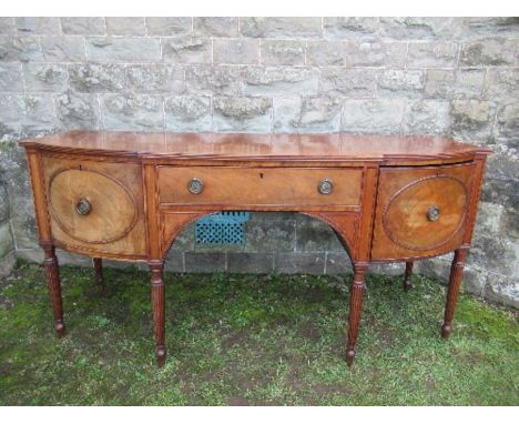 A Regency mahogany bow front sideboard, fitted with a central drawer flanked by cupboard doors, opening to reveal a cellarett