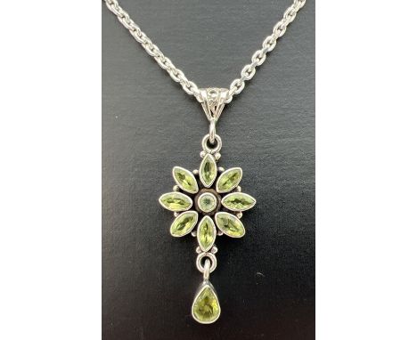 A silver and peridot flower design pendant on an 18" silver belcher chain. Pendant stamped 925 to reverse and measures 5cm lo