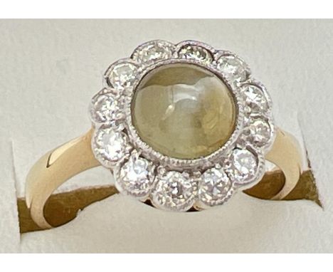 An antique 18ct gold Cats eye chrysoberyl &amp; diamond ring. Central circular cats eye cabochon surrounded by a halo of 12 d