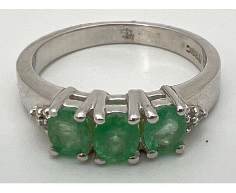 A Genuine Gem Company silver and emerald trilogy ring with diamond clusters set to each shoulder. Inside of band stamped 925 