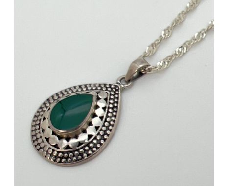 A 925 silver tear drop shaped pendant set with central green stone and with decorative mount. On an 18" silver singapore chai