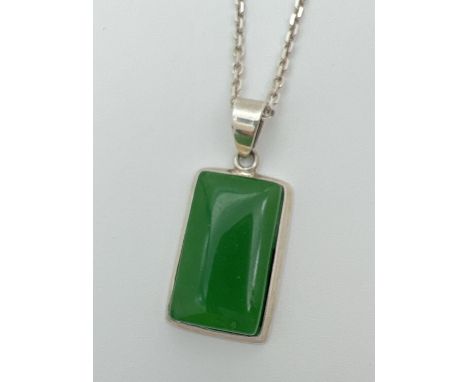 A rectangular shaped apple green jade and 925 silver pendant necklace. Pendant on an 18" silver belcher style chain with spri