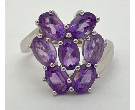 A Genuine Gem Company silver and amethyst large dress ring. Set with 7 oval cut amethysts in a twisted setting. Ring size NÂ½