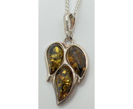 A green amber set leaf shaped pendant in white metal mount, on a 20" 925 silver chain with spring ring clasp. 