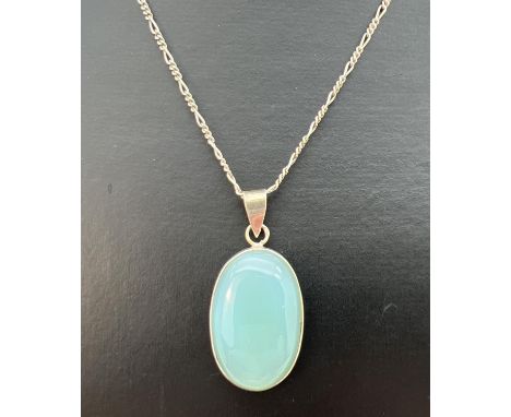 An oval shaped pale blue natural stone pendant in white metal mount, on an 18" silver figaro chain. Stamped 925 to joining li