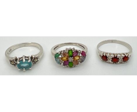 3 silver stone set dress rings. An unmarked multi stone ring in a floral style setting (size MÂ½), a blue stone and marcasite