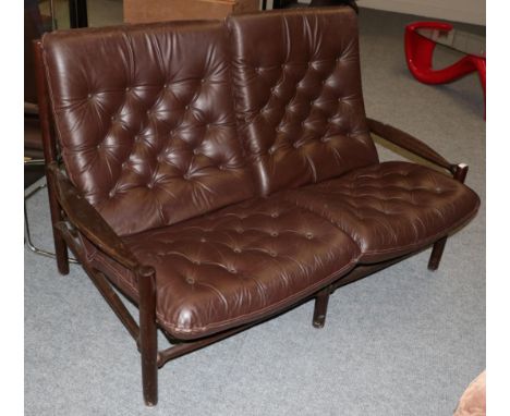 A 1970's Danish Design Two-Seater Sofa, covered in buttoned brown leather, with four cushions, 146cm by 86cm by 92cm