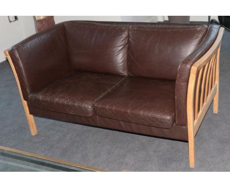 A 1970's Danish Stouby Two-Seater Sofa, upholstered in brown leather and with six cushions, on square form legs below slatted