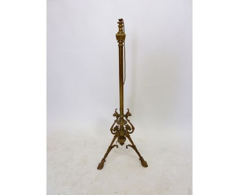 A 19th century brass extending standard lamp base with scrollwork and triple hoof feet 