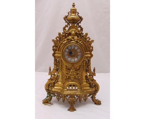 A French late 19th century gilt metal mantle clock, scroll pierced and chased with scrolls and masks, enamel dial with Roman 