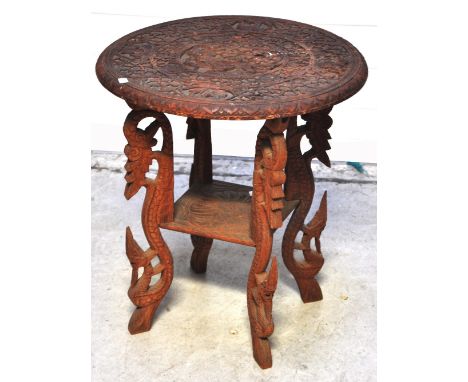 An early 20th century carved hardwood Oriental circular table decorated with mythical birds, dragons and elephants on four su