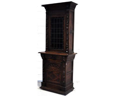 A late 19th/early 20th century heavily carved oak glazed bookcase with lower cupboard with one interior shelf, 220 x 90cm.