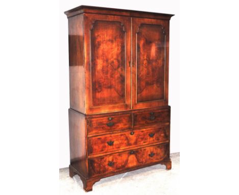 An early 20th century walnut linen press, the moulded cornice above two cupboard doors enclosing two later shelves above a ba