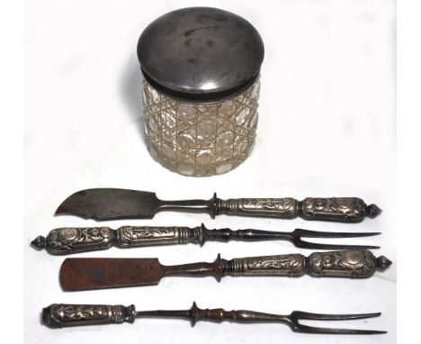 A cut glass trinket pot with a hallmarked silver top (marks rubbed) and four white metal handle cutlery pieces.