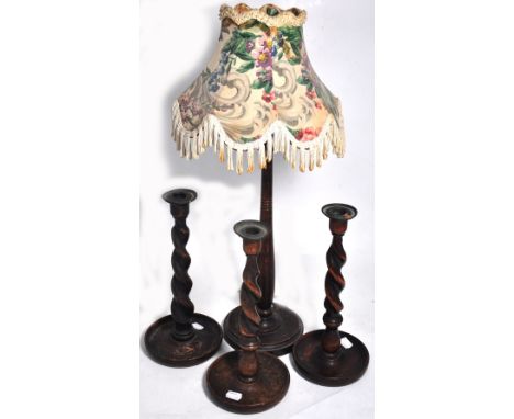 Three early 20th century barleytwist candlesticks, height 31cm and a turned wooden lamp with floral shade, height 35cm (4).