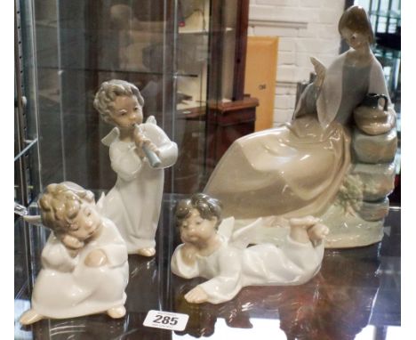 Three Lladro musical cherubs and a large Nao figurine of a lady reading a book (her head is damaged) 