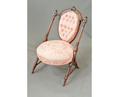 A LATE VICTORIAN WALNUT NURSING CHAIR, the arched back with foliate carved cresting rail above an oval button back flanked by
