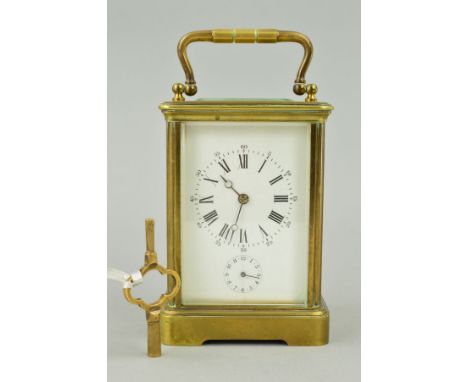 AN EARLY 20TH CENTURY FRENCH BRASS CASED ALARM CARRIAGE CLOCK, with carrying handle above oval glazed panel, the white enamel