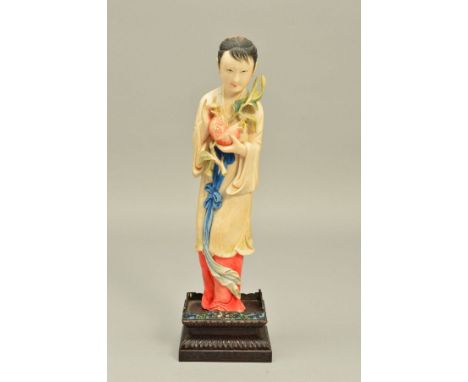 AN EARLY 20TH CENTURY JAPANESE CARVED IVORY FIGURE OF A GIRL HOLDING A POMEGRANATE, stained details to hair and robes with gi