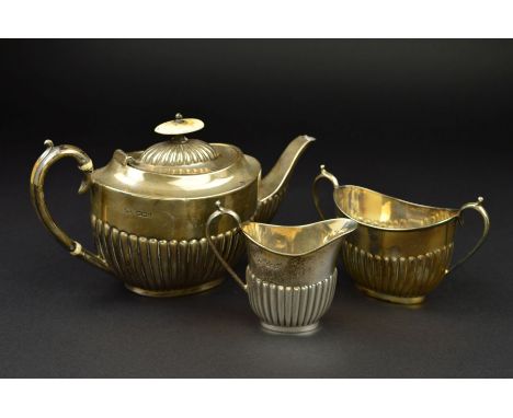 A LATE VICTORIAN SILVER BACHELOR'S THREE PIECE TEASET, of oval form, part reeded to lower half of bodies, ivory finial and in