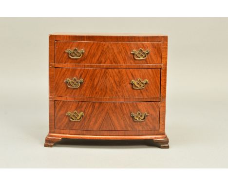 A 20TH CENTURY MINIATURE WALNUT VENEERED BOW FRONT CHEST OF THREE LONG DRAWERS, with gilt metal pierced brass handles, on oge