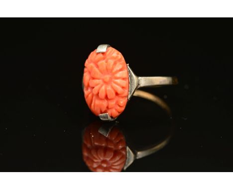 AN EARLY 20TH CENTURY CARVED CORAL RING, an oval floral panel measuring approximately 15mm x 10mm, ring size N, stamped '9ct 