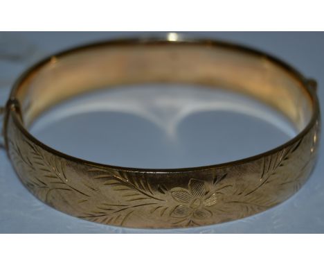 A 9ct gold hinged bangle, engraved and chased with foliage, 28.7oz