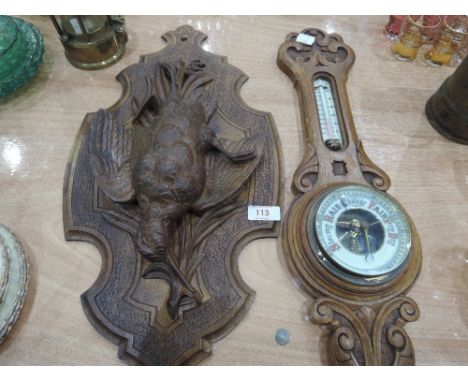 A Blackforest style carved wall plaque depicting hanging Woodcock and a carved oak framed barometer