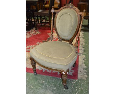 A Victorian mahogany nursing chair, oval padded back, turned uprights, stuffed overseat, turned forelegs, ceramic casters.