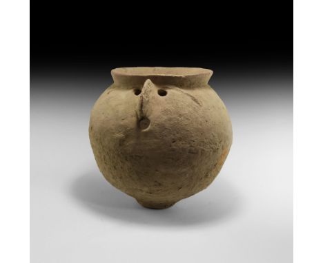 1st-2nd century AD. A ceramic urn with bulbous body, flared rim and narrow base, applied brow ridge and nose below the rim wi