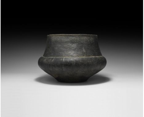 Late 2nd millennium BC. A burnished ceramic jar with carination to the shoulder, shallow vertical ribs and lentoid bosses, br