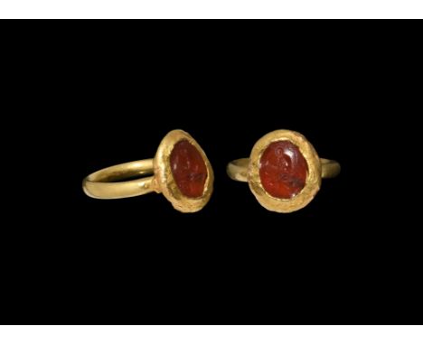 2nd-3rd century AD. A gold finger ring with round-section hoop and irregular sheet gold cell, hollow-formed with inset carnel