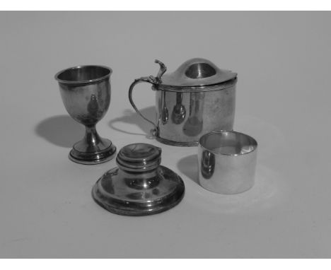 Four small silver items including a lidded mustard pot, napkin ring, egg cup and inkwell, various dates and makers, approx. c