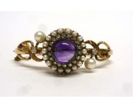 A late 19th/early 20th century Etruscan-style yellow metal bangle set centrally with a cabochon cut amethyst within a border 