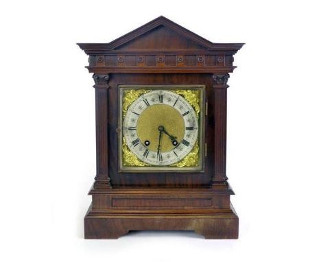 An early 20th century walnut mantle clock, in an architectural case, with a brass and silvered dial, Roman numerals and an ei