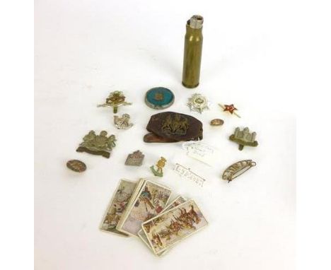 A selection of military collectibles and ephemera including Manchester, Cambridgshire and North Staffordshire cap badges, sho