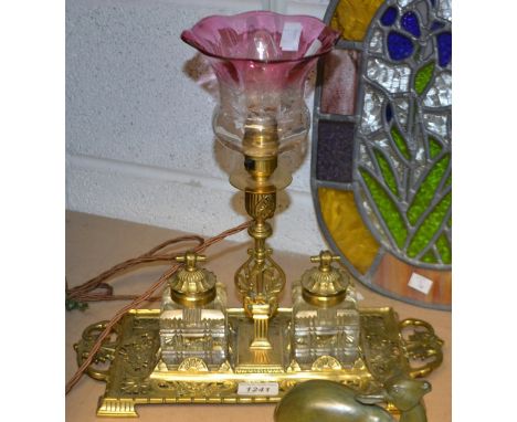 A late 19th century style lacquered brass desk standish, the central lamp flanked by a pair of cut glass ink wells, pierced b