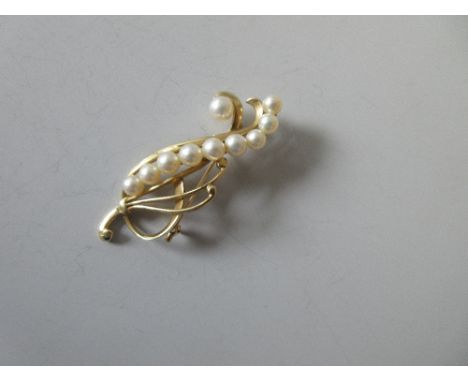 A cultured pearl brooch by Mikimoto, designed as a stylised spray, with a 6mm pearl to one side of a serpentine line of nine 