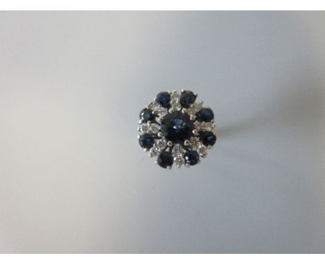 A sapphire and diamond sunburst cluster ring, set to the centre with a round cut sapphire with eight radiant lines each with 